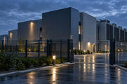 Synthetic editorial illustration. Unbranded data-centre exterior with cooling infrastructure and secure perimeter for cybersecurity news.