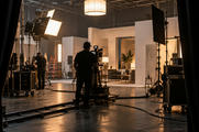 Synthetic editorial illustration. Unbranded television and film production stage with studio lighting for media and streaming news.