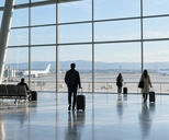 Synthetic editorial illustration. Unbranded airport terminal with blank aircraft silhouettes beyond the glass for travel, tourism and airline news.