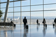 Synthetic editorial illustration. Unbranded airport terminal with blank aircraft silhouettes beyond the glass for travel, tourism and airline news.