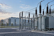 Synthetische illustratie van transformatoren en netaansluitingen naast een generiek datacentrum.