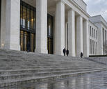 Synthetic editorial illustration. Unbranded civic building with stone columns and broad steps for regulation, courts and trade-policy news.