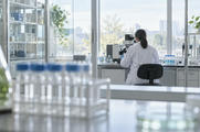 Synthetic editorial illustration. Anonymous researcher working with an unbranded optical instrument in a bright biotech laboratory.