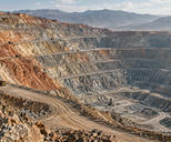 Synthetic editorial illustration. Open-pit copper mine with haul roads and terraced earthworks for mining and metals-market news.