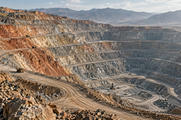 Synthetic editorial illustration. Open-pit copper mine with haul roads and terraced earthworks for mining and metals-market news.