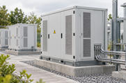 Synthetic editorial illustration. Installed equipment enclosures are connected by supported conduits beside transformer equipment.