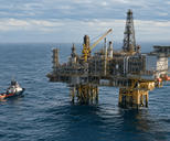 Synthetic editorial illustration. Generic offshore energy platform with processing pipework and a small service vessel on a calm sea; no real named facility or discovery.