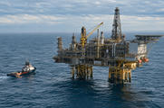 Synthetic editorial illustration. Generic offshore energy platform with processing pipework and a small service vessel on a calm sea; no real named facility or discovery.