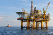 Synthetic editorial illustration. An offshore platform is framed over open water with a service vessel standing off to one side.