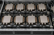 Synthetic editorial illustration. Eight rectangular metal-covered modules sit in two rows inside an open server tray. Black cooling hoses connect them to metal fittings and a side manifold under soft inspection light.