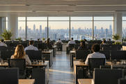 Synthetic editorial illustration. An open-plan office overlooks a broad city skyline through tall windows. Rear-facing analysts sit at rows of desks with dark monitors, plants and chairs arranged along a central aisle.