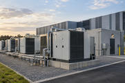 Synthetic editorial illustration. Visually generic modular industrial power units and practical utility connections beside an anonymous data facility; no named fuel-cell or generator design.