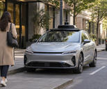 Synthetic editorial illustration. Generic unbranded electric passenger car with modest rooftop sensing equipment at an anonymous urban pickup bay; no real named vehicle, company or incident.