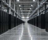 Synthetic editorial illustration. A data-centre hall contains long rows of black equipment racks. Tiny green and amber lights flank a broad polished aisle where a small rear-facing worker walks beneath cable trays.