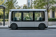 Synthetic editorial illustration. Generic purpose-built bidirectional passenger shuttle with symmetrical body, integrated discreet sensors and passenger seating but no visible steering wheel or driver controls; not a converted conventional passenger saloon. No actual named company, product, site, person or incident is depicted.