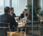 Synthetic editorial illustration. A documentary view through glass into a corporate board meeting with anonymous executives seated naturally around an ordinary table, papers seen from blank backs, no theatrical empty throne or handshake.