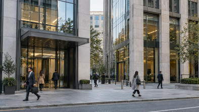 Synthetic editorial illustration. A street-level documentary view of two adjacent anonymous financial-office buildings with a few commuters, neutral stone and glass façades, no logos, bank names or symbolic miniature buildings.
