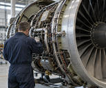 Synthetic editorial illustration. A technician seen from behind inspecting a credible aircraft-engine assembly in a functioning aerospace workshop, real machined metal components and practical fixtures, natural industrial daylight.
