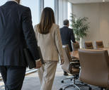 Synthetic editorial illustration. A calm observational scene of anonymous executives entering a functional corporate meeting room, one person holding a closed plain folder, no identifiable faces, no staged handshake or ceremonial pose.