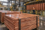 Synthetic editorial illustration. A copper processing facility with realistic thick copper cathode plates stacked in bundles and machinery deeper in the building, natural industrial light and tactile metal surfaces.