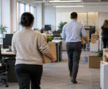 Synthetic editorial illustration. An ordinary office-floor relocation in progress, anonymous staff seen from behind carrying plain archive boxes between desks, calm workaday atmosphere and real office architecture, no dramatised layoffs.